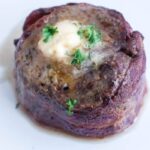 Air Fryer Filet Mignon on a plate with butter and fresh parsley on top