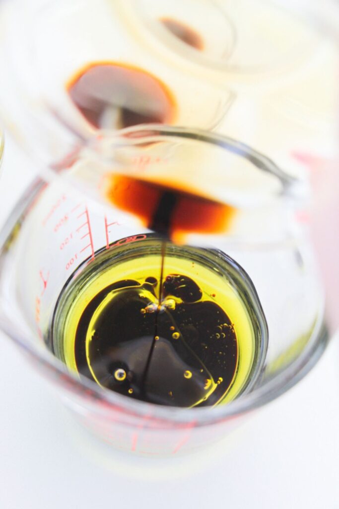balsamic glaze pouring into a measuring cup with oil