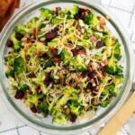 Amish Broccoli Salad in a bowl with a wooden spoon to the side of bowl