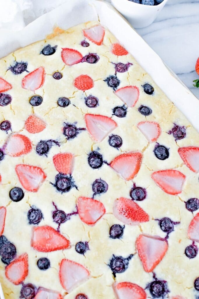 overhead picture of sheet pan pancakes baked and topped with blueberries and strawberries