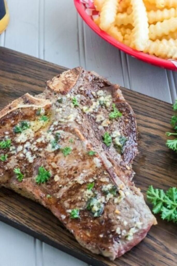 steak on a cutting board with fresh herbs sprinkled on top