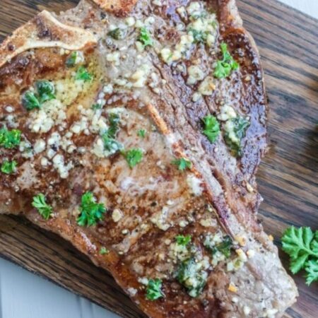 tbone steak with herbs and butter on a cutting board