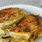 Cabbage steaks on a white plate on counter