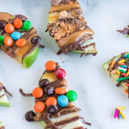 Caramel Apple Slices on table decorated with crushed candy and mini M&Ms