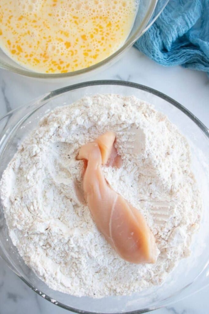 chicken tenderloin sitting on a flour mixture on plate