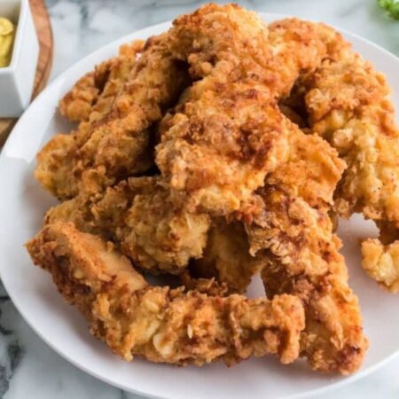 Homemade Chicken Strips on a plate stacked on top of one another
