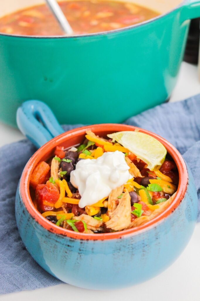 bowl of chicken tortilla soup with sour cream on top and lime wedge in bowl
