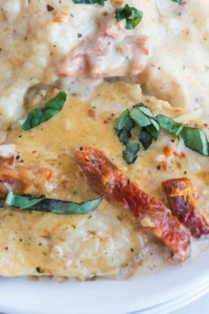 Marry Me Chicken on a plate with basil and sundried tomatoes on top of the chicken