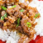 close up of orange chicken on plate with rice underneath