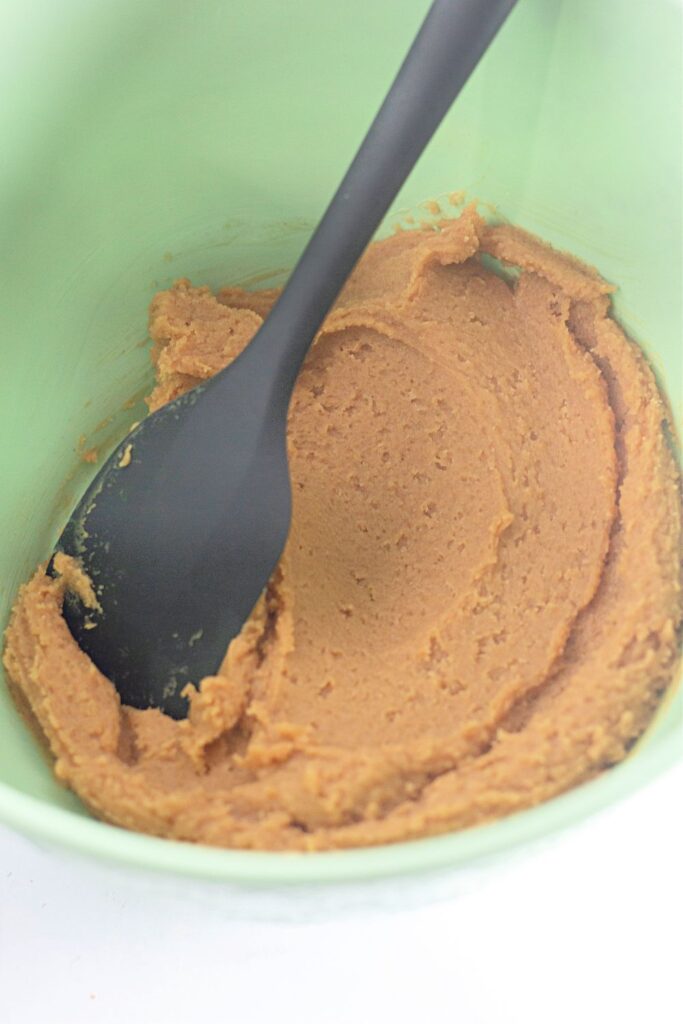 mixed up cookie dough in a green bowl with a spatula