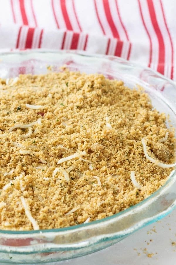 side view of breadcrumbs in pie dish with a few onions on it