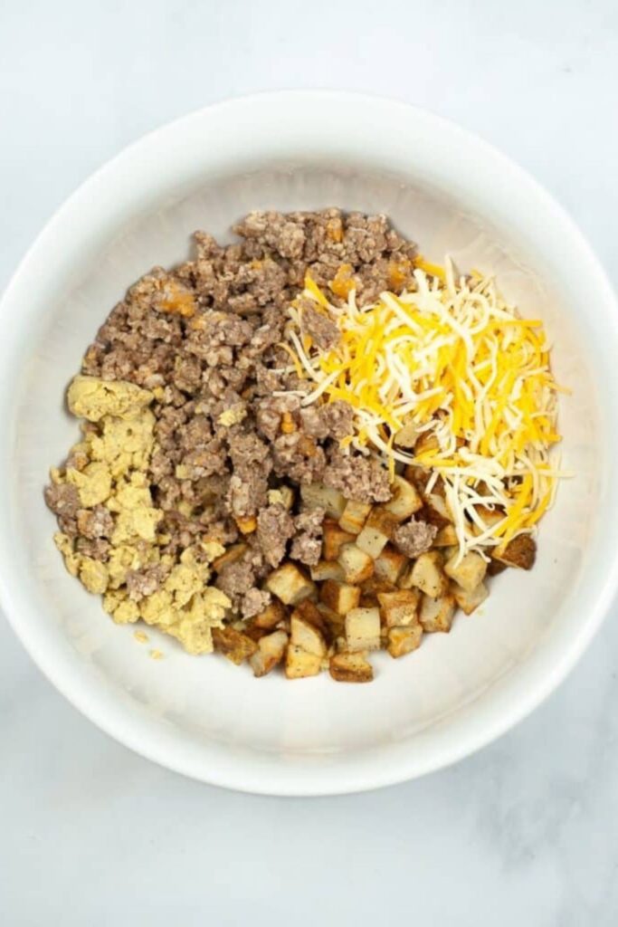 white bowl full of sausage, cheese, eggs, potatoes, for making Breakfast Chimichangas