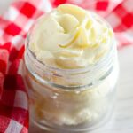 homemade butter in a small mason jar on table with red checkered towel behind jar