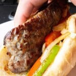 holding brat in hand on hoagie