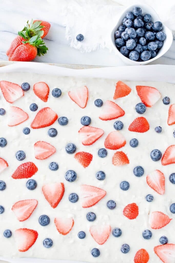sheet pan pancakes with berries and strawberries on top of the pancake batter in a pan