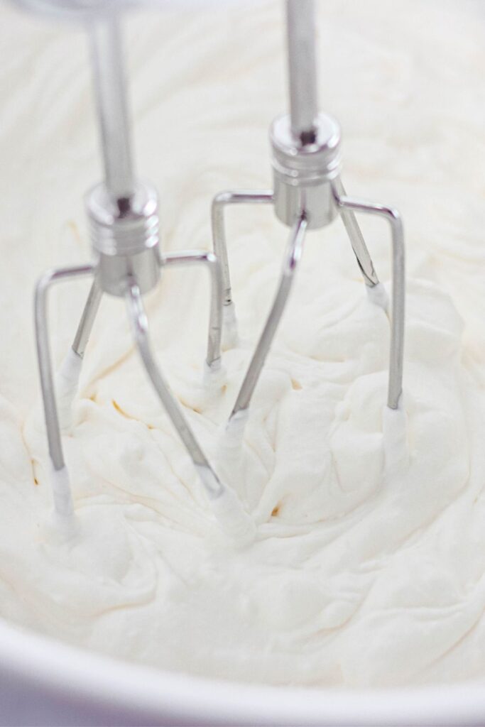 mixer whisks in a bowl with whipped cream