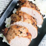 a black plate with some slices of cooked Marinated Air Fryer Pork Tenderloin