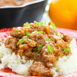 orange chicken on plate with rice and oranges in background