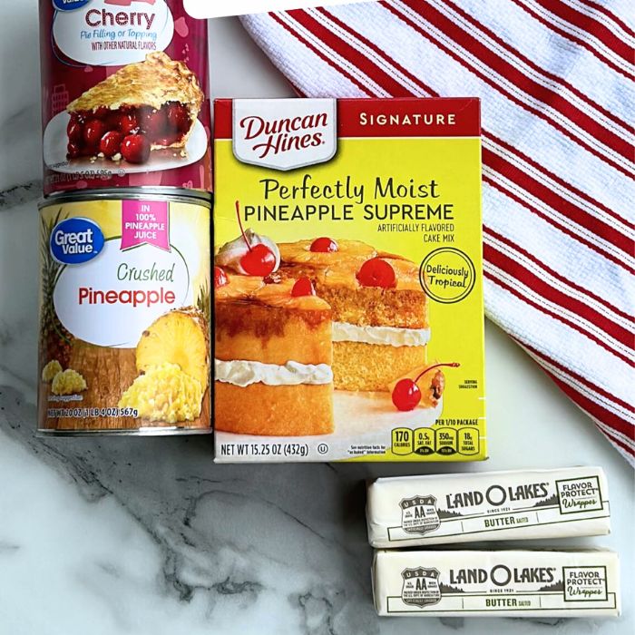 pie filling, pineapple, and cake mix and sticks of butter on table with towel behind it