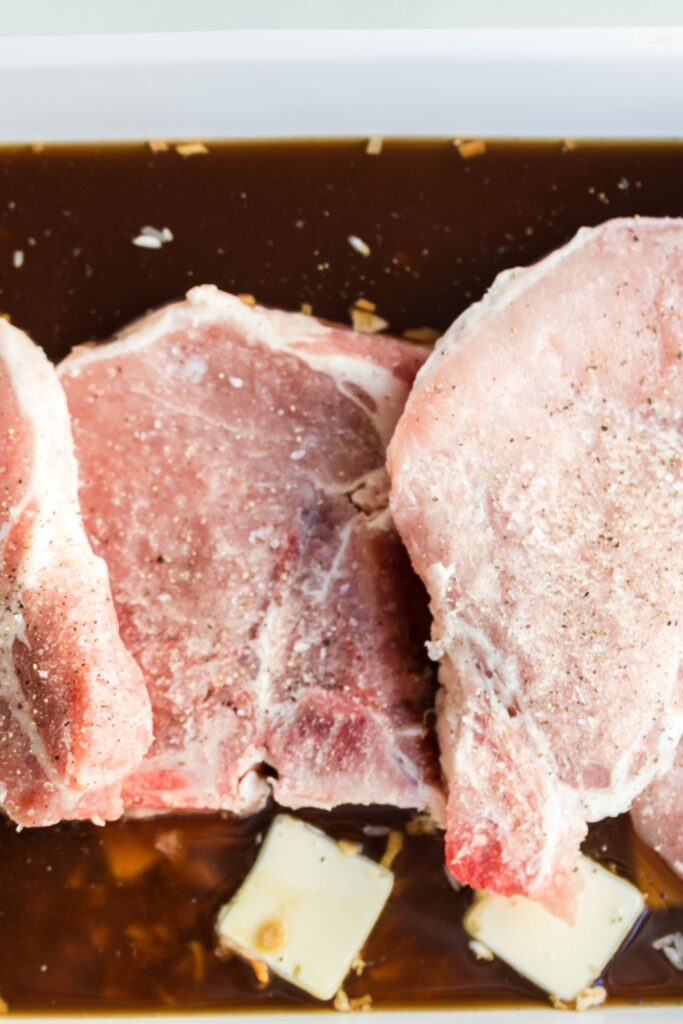 pork chops in a baking dish that is seasoned with salt and pepper