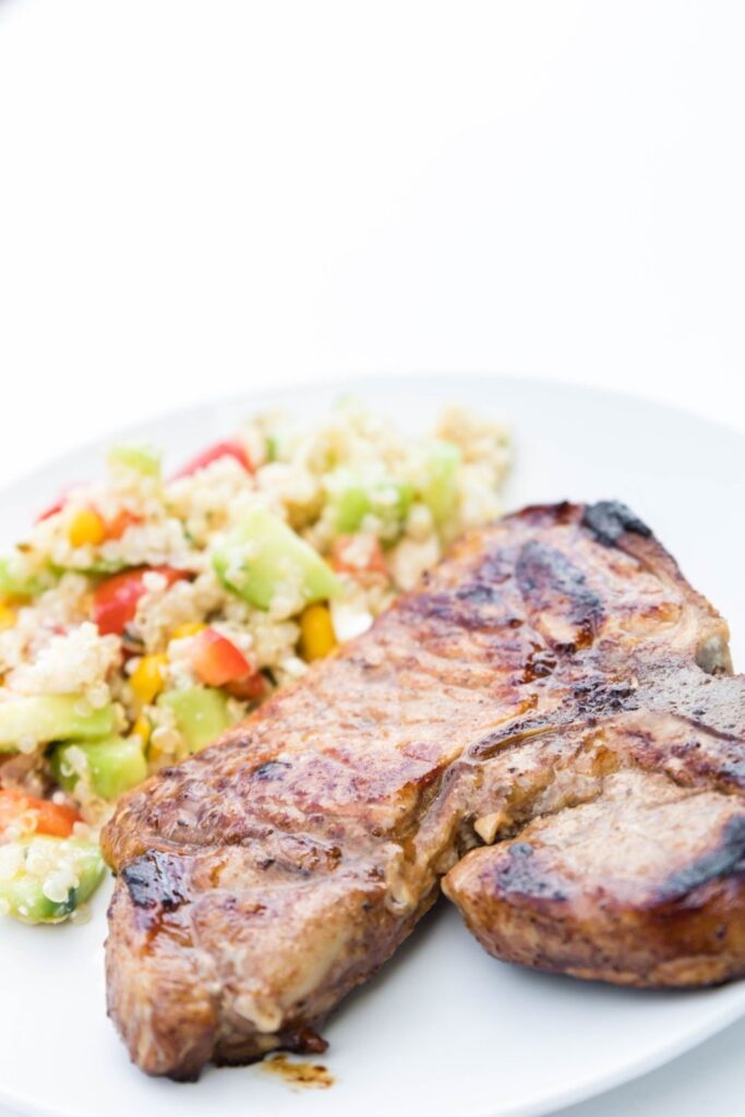 pork chop on plate with quinoa salad on side