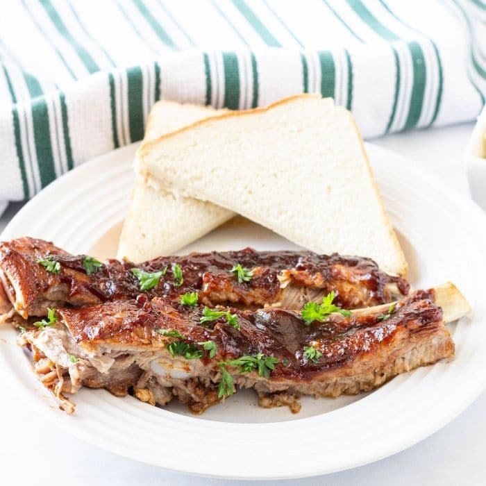 Plate with pork ribs and Texas toast behind it with a towel behind it