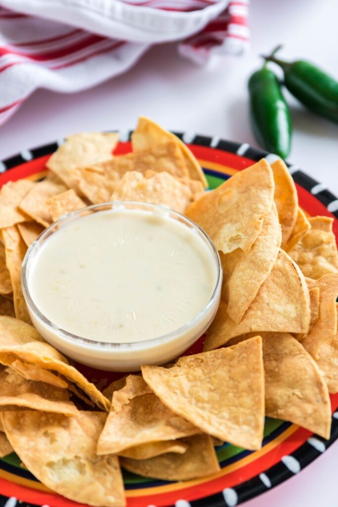 white cheese dip in a bowl with tortilla chips around it