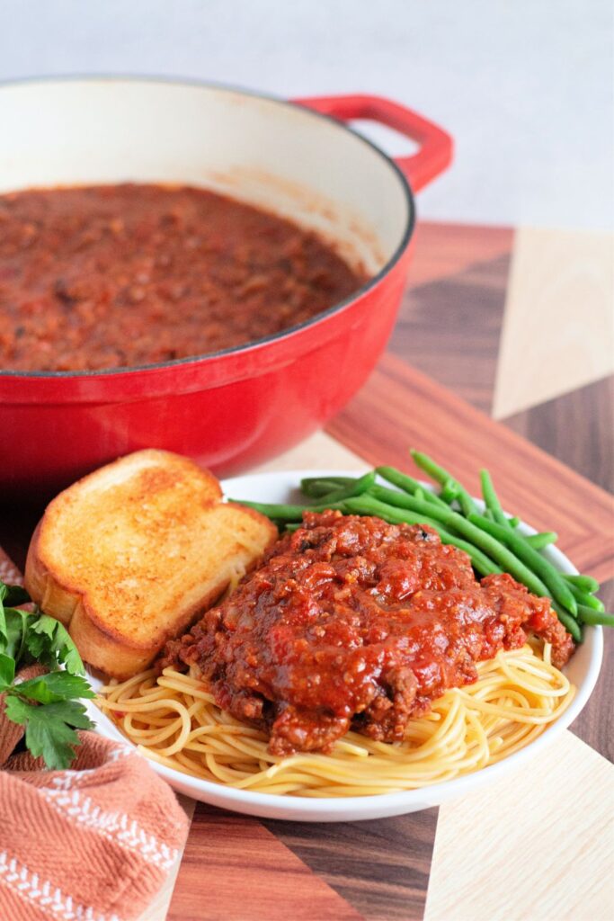 plate of spaghetti and sauce with garlic bread and green beans on the side