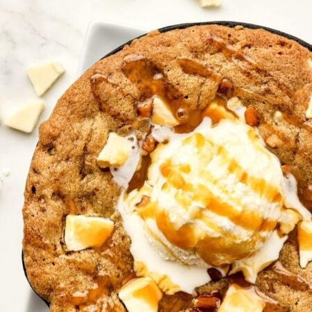 Salted Caramel Cookie Skillet on the table with a scoop of ice cream and caramel sauce on top