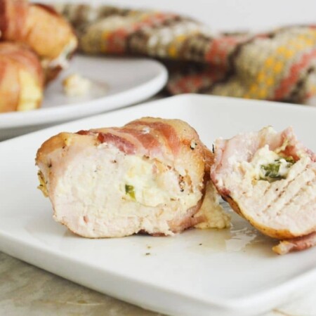 bacon wrapped chicken on a white plate on table