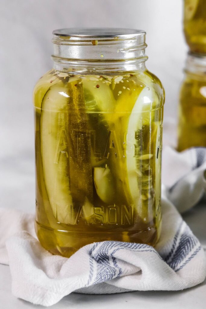 sweet horseradish pickles in a jar with towel under it on table