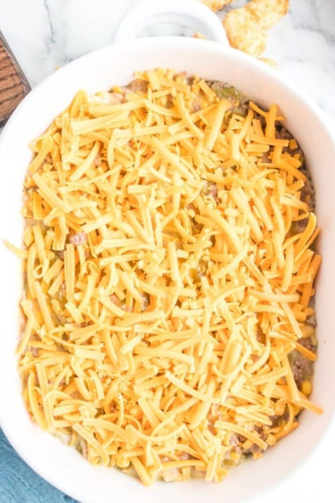 Tater Tot Casserole in pan with shredded cheese on top