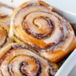 cinnamon roll in pan being lifted out by spatula