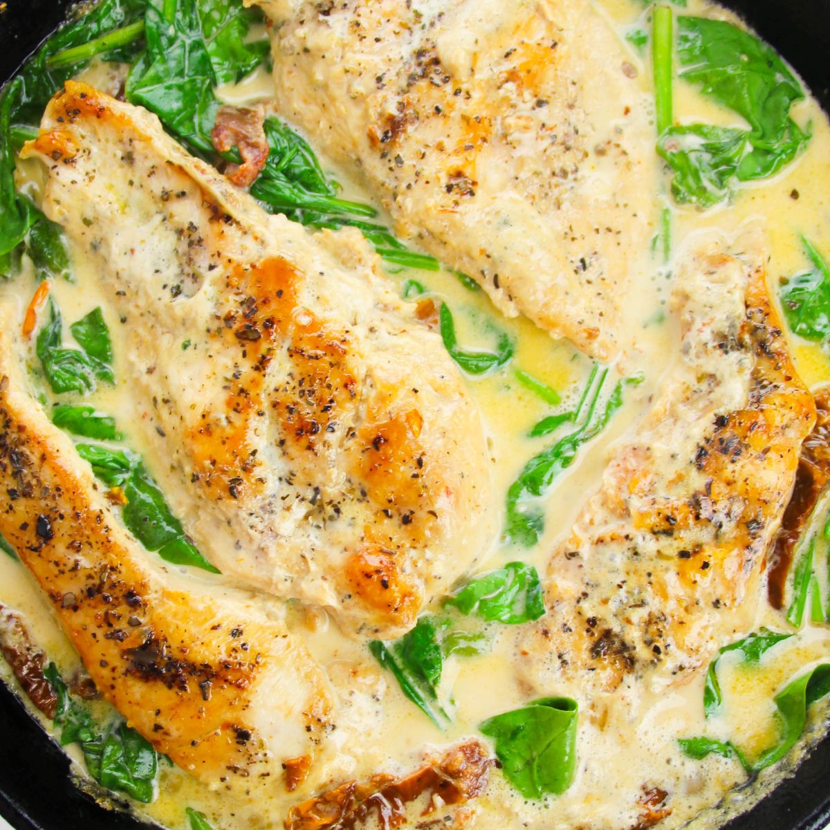 Tuscan Chicken in a pan with sauce and spinach on it