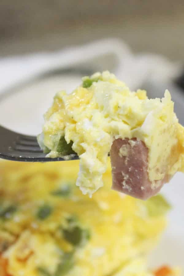 Serve up this baked western omelette for breakfast, lunch, or dinner! Easy prep, and within no time you have a fluffy egg omelet baked in the oven. #western #denver #omelette #easy #baked #casserole #peppers #cheese #breakfastcasserole #recipe #ham #bake #simple #Athome #lunch #healthy breakfast omelette on a fork