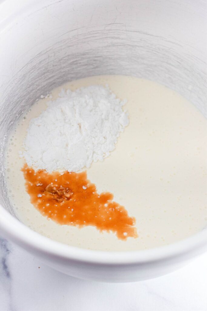 heavy cream, powdered sugar and vanilla in a metal bowl on table