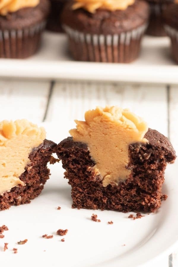 zucchini cupcake cut in half with peanut butter frosting in center and on top